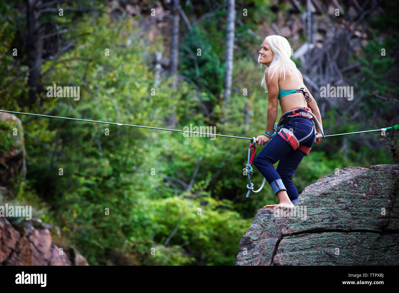 Side view of woman holding rope while standing on rock Stock Photo