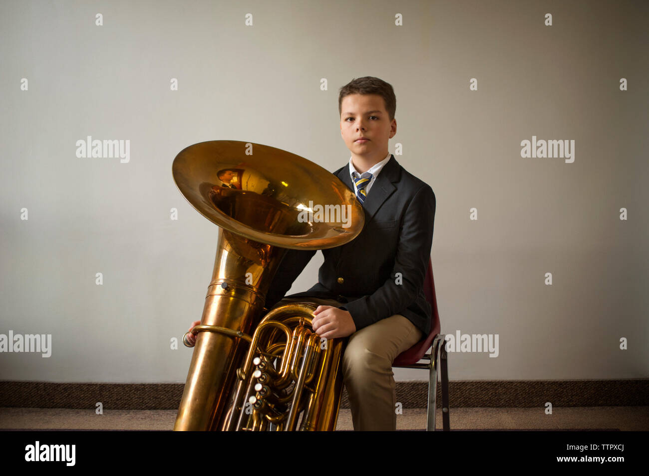 Portrait of confident boy with tuba against white wall Stock Photo