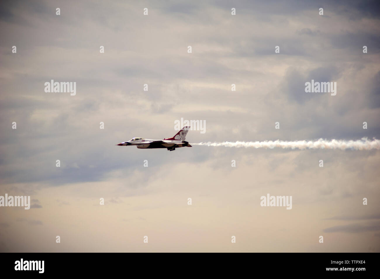 Low angle view of fighter plane flying in cloudy sky Stock Photo