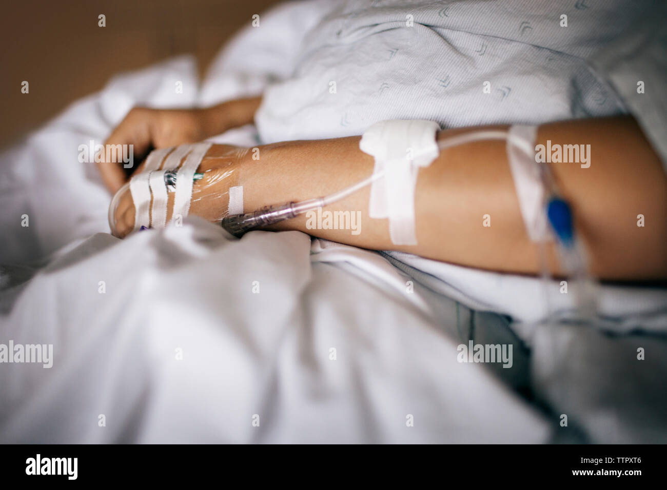 IV drips attached to woman's hand in hospital Stock Photo
