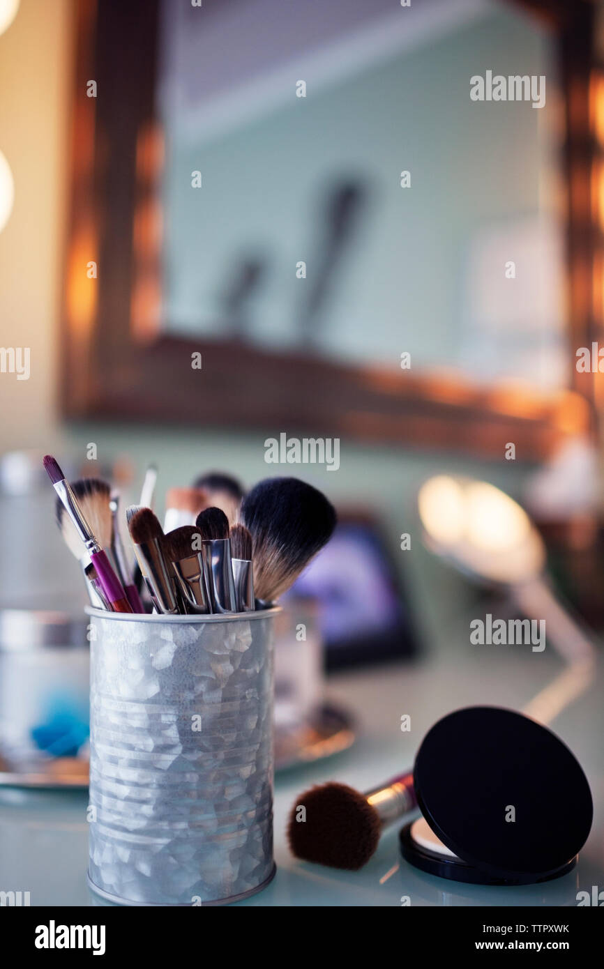 Makeup brushes in container on vanity table Stock Photo