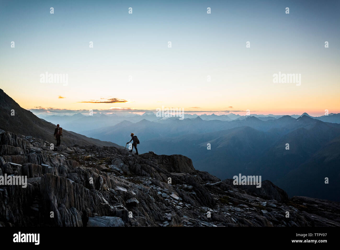 Two climbers in front of a vast mountain scene at dusk in New Zealand Stock Photo