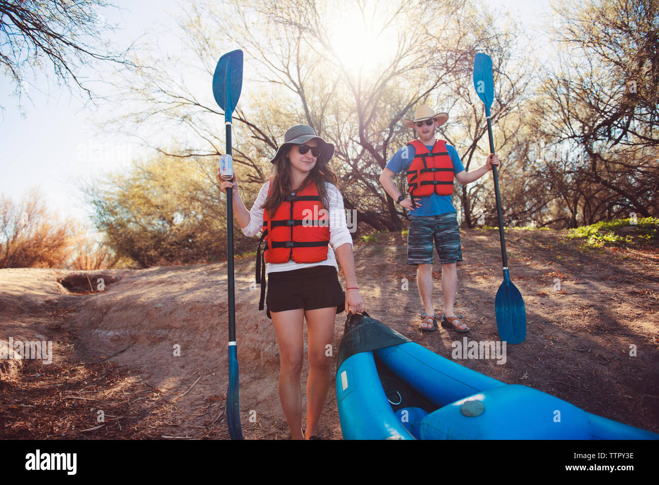 Male and female friends holding oars on shore Stock Photo