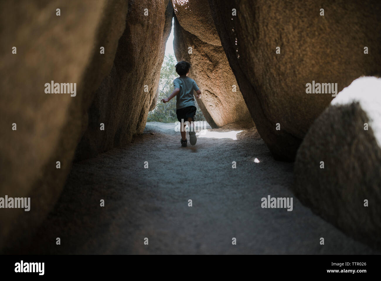 Rear view of boy running under rock formations at Joshua Tree National Park Stock Photo