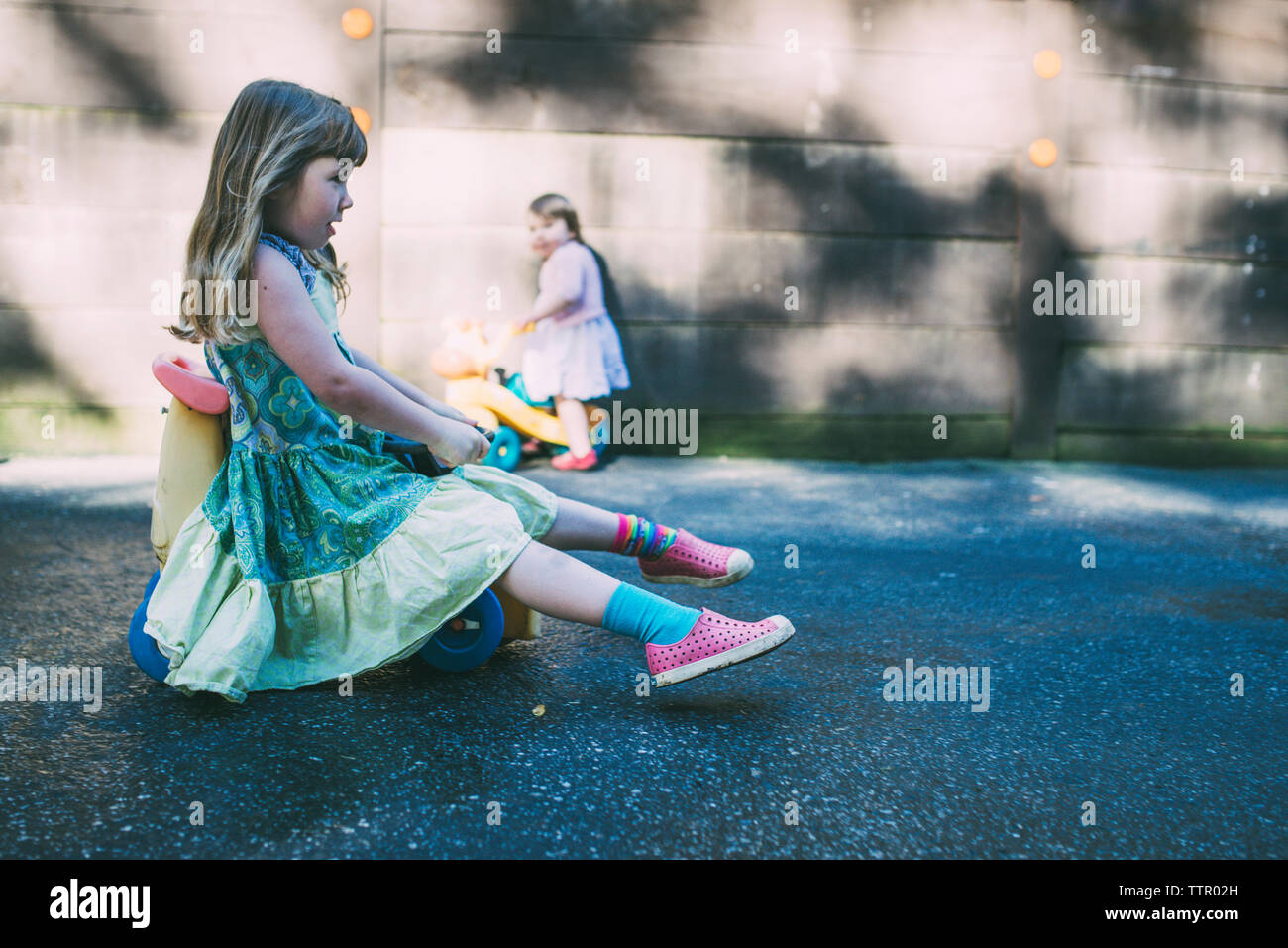 Side view of girls riding tricycles on road Stock Photo Alamy