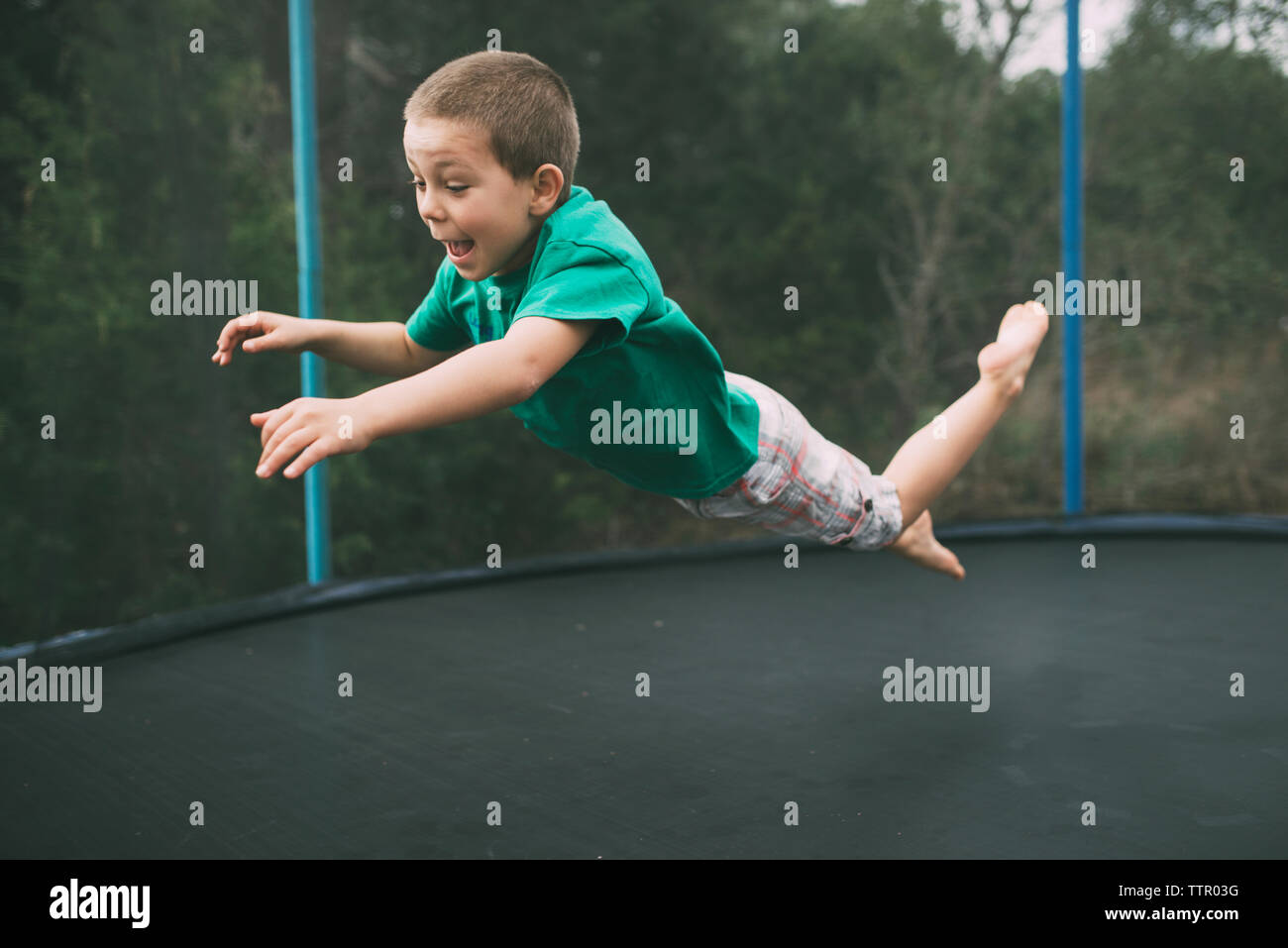 Playful boy jumping on trampoline at playground Stock Photo