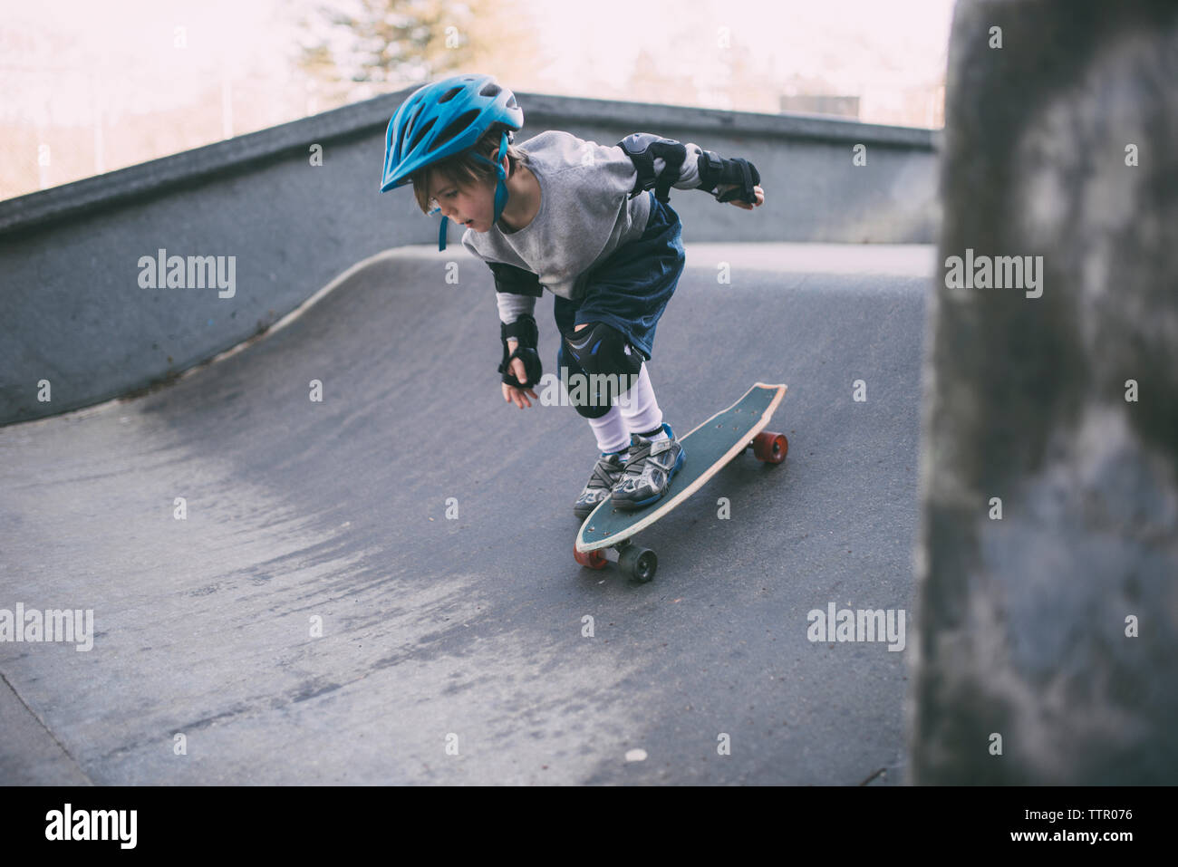 Carefree boy skateboarding on sports ramp at skateboard park Stock Photo
