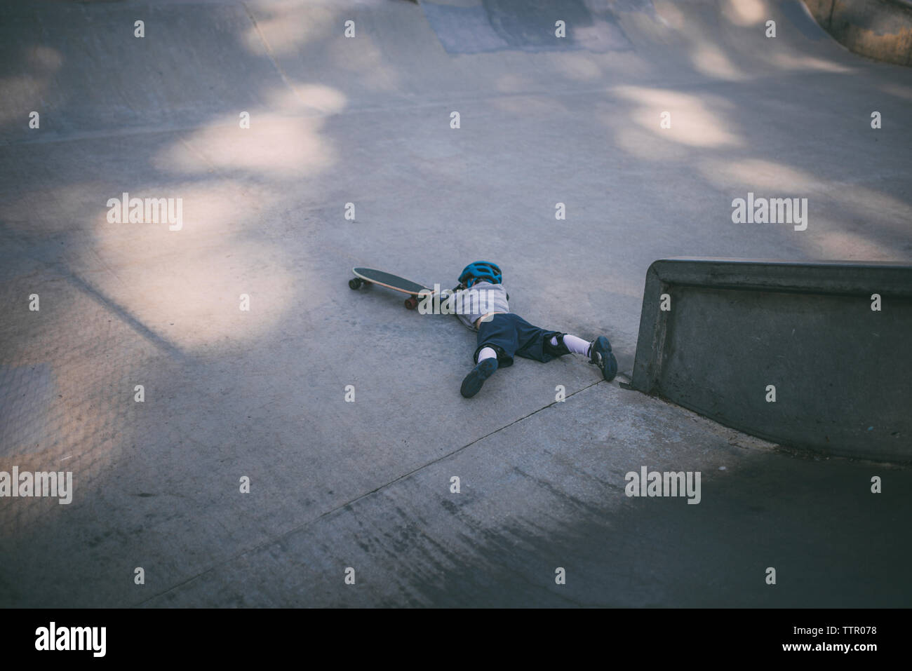 High angle view of boy falling from skateboard at park Stock Photo