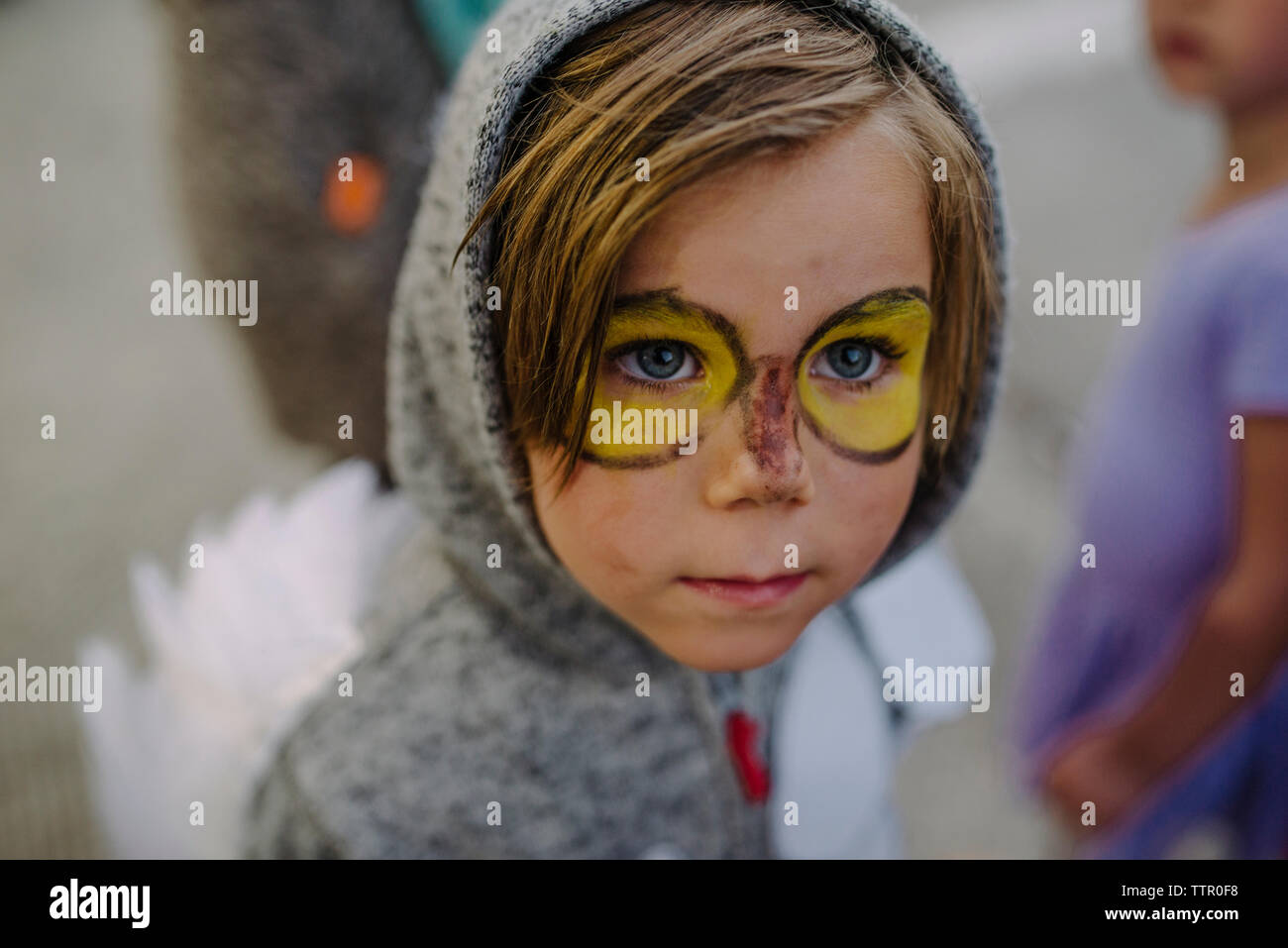 Cute boy with face paint wearing costume looking away during Halloween party Stock Photo
