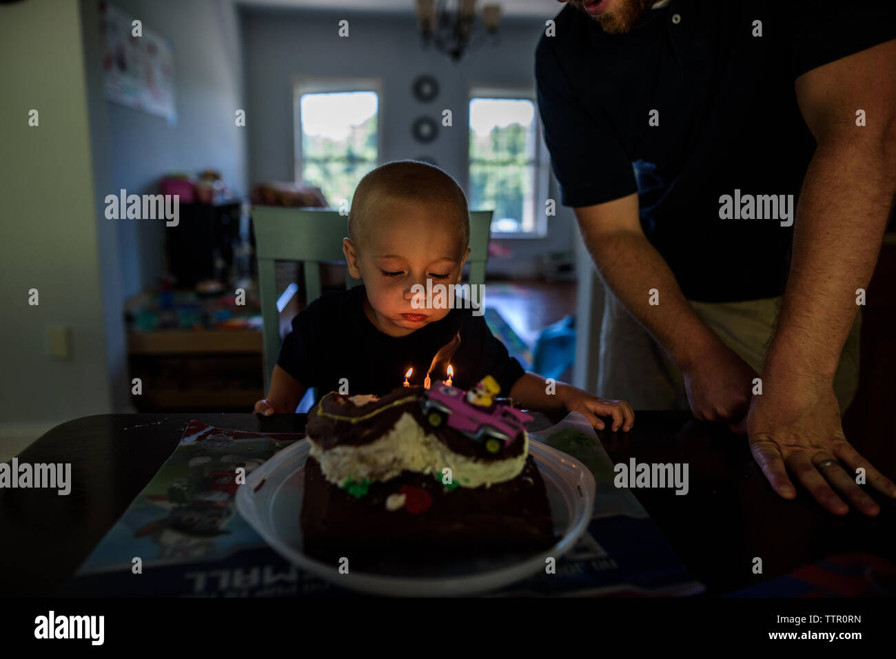 young boy blowing out candles on birthday cake with dad nearby Stock Photo Alamy