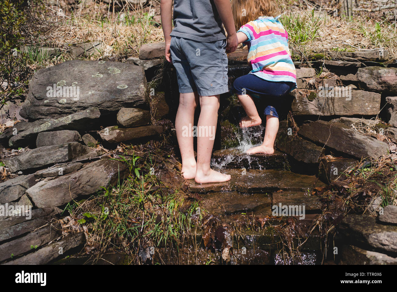 Low section of brother standing by sister cleaning legs through