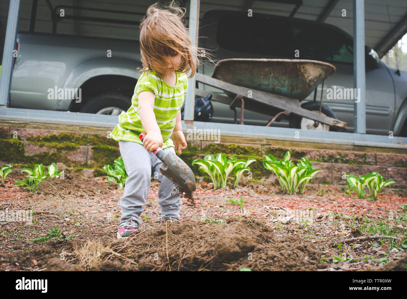 Girl digging soil with trowel while standing in garden Stock Photo