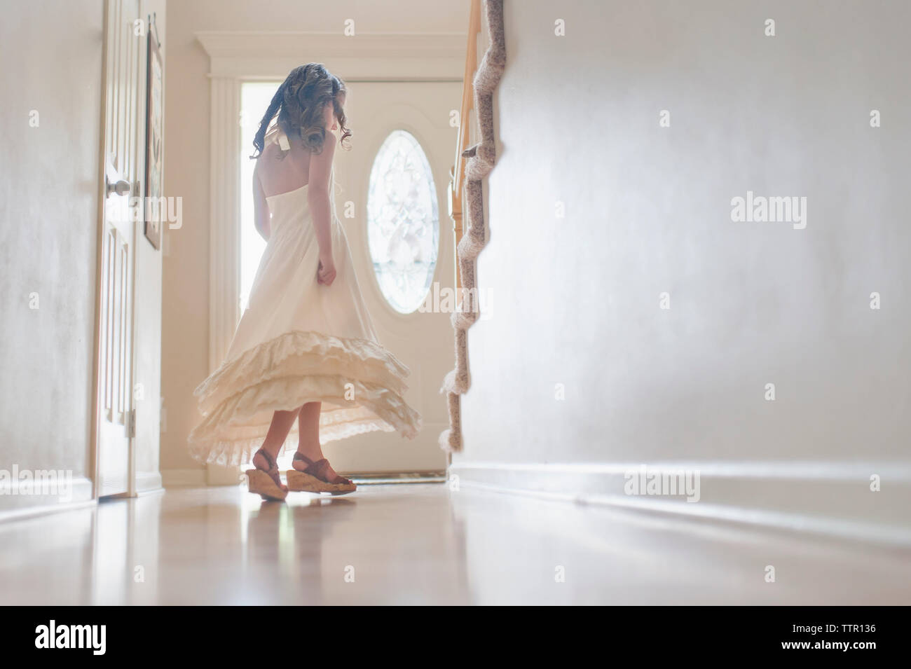 Girl in dress spinning by door at home Stock Photo