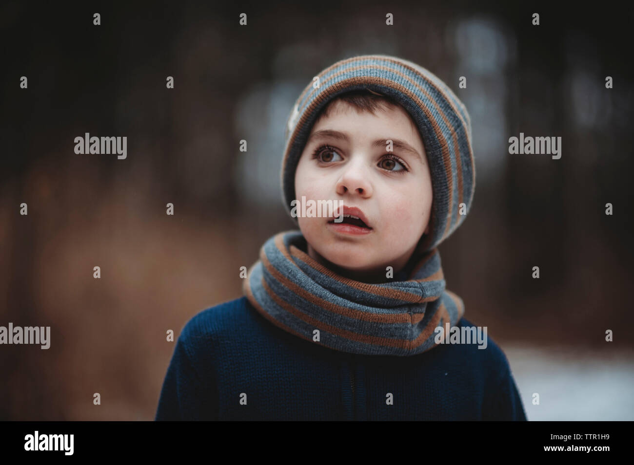 Thoughtful boy looking away while standing at park Stock Photo