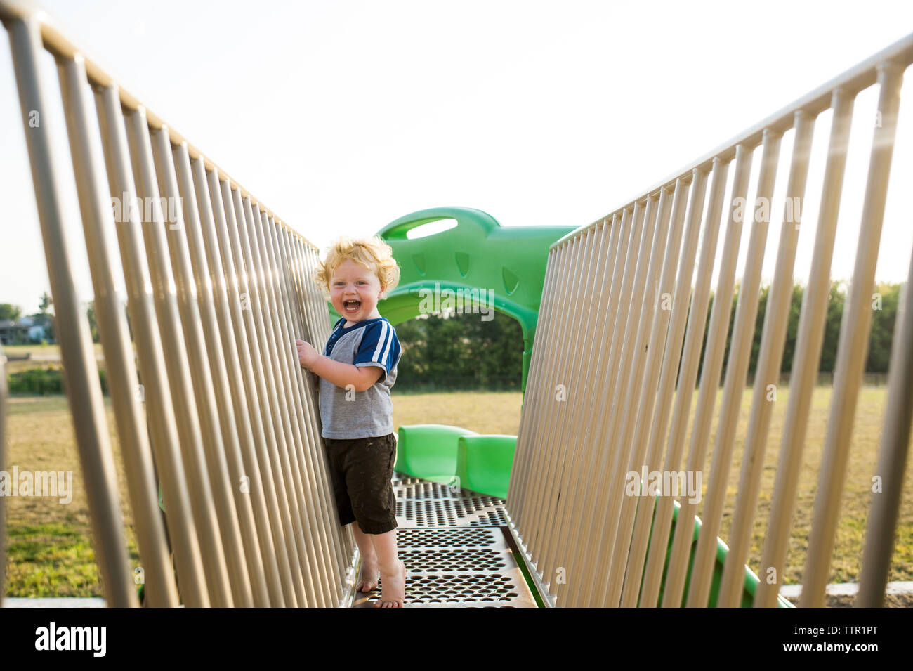 Portrait of cute cheerful baby boy playing on outdoor play equipment at playground Stock Photo