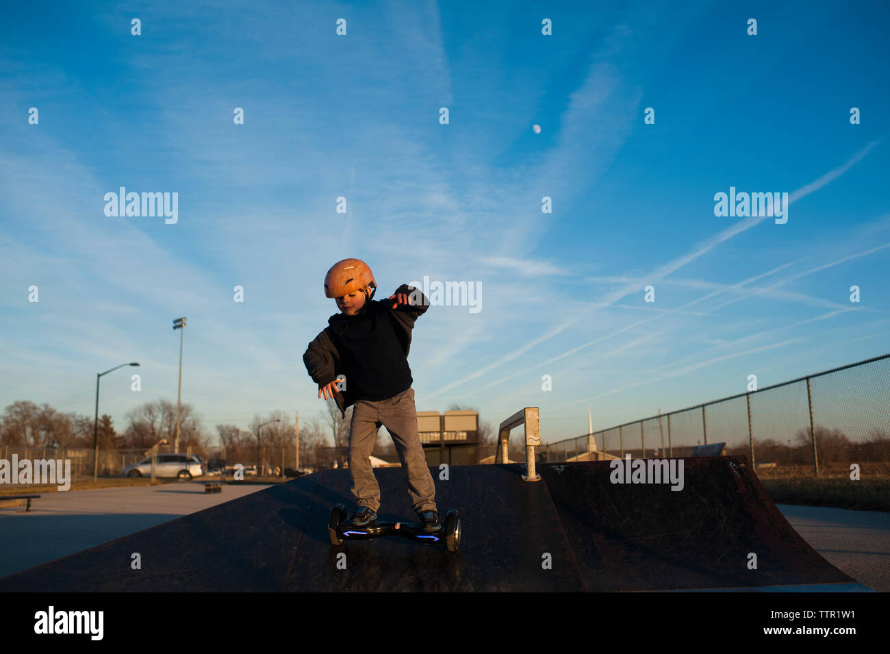 Young boy riding down ramp at skatepark against blue sky Stock Photo ...