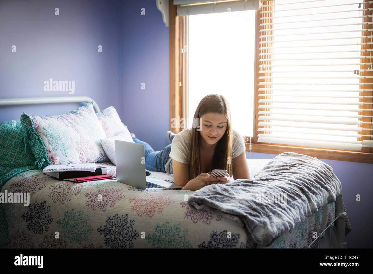 Girl lying on bed and using smart phone at home Stock Photo - Alamy