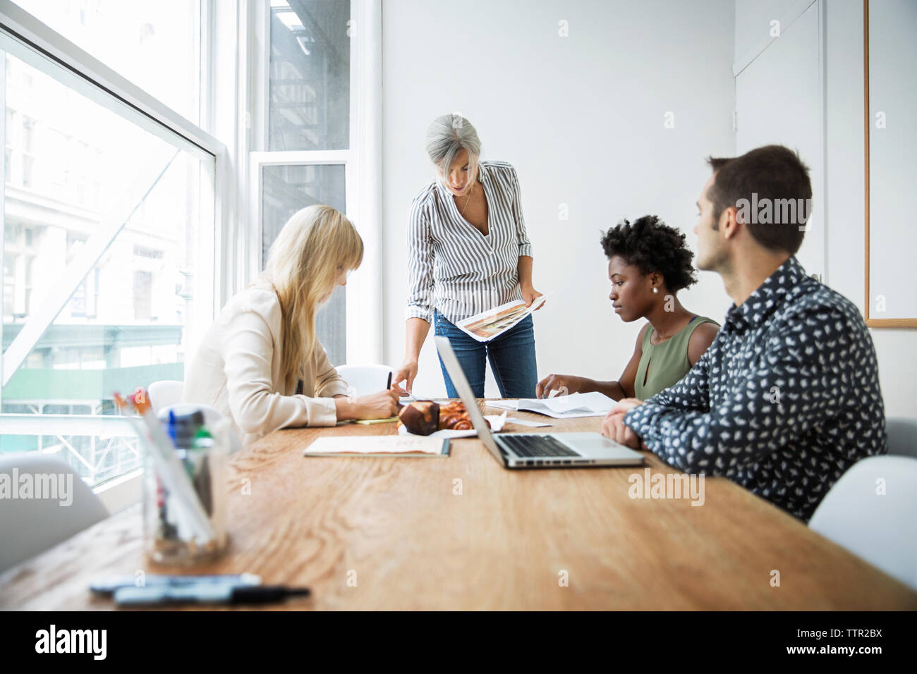 Female manager discussing strategy with executives in board room Stock Photo