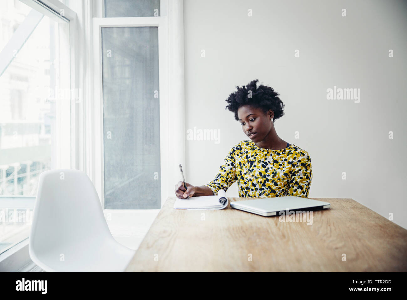 Businesswoman writing in book at desk in board room Stock Photo