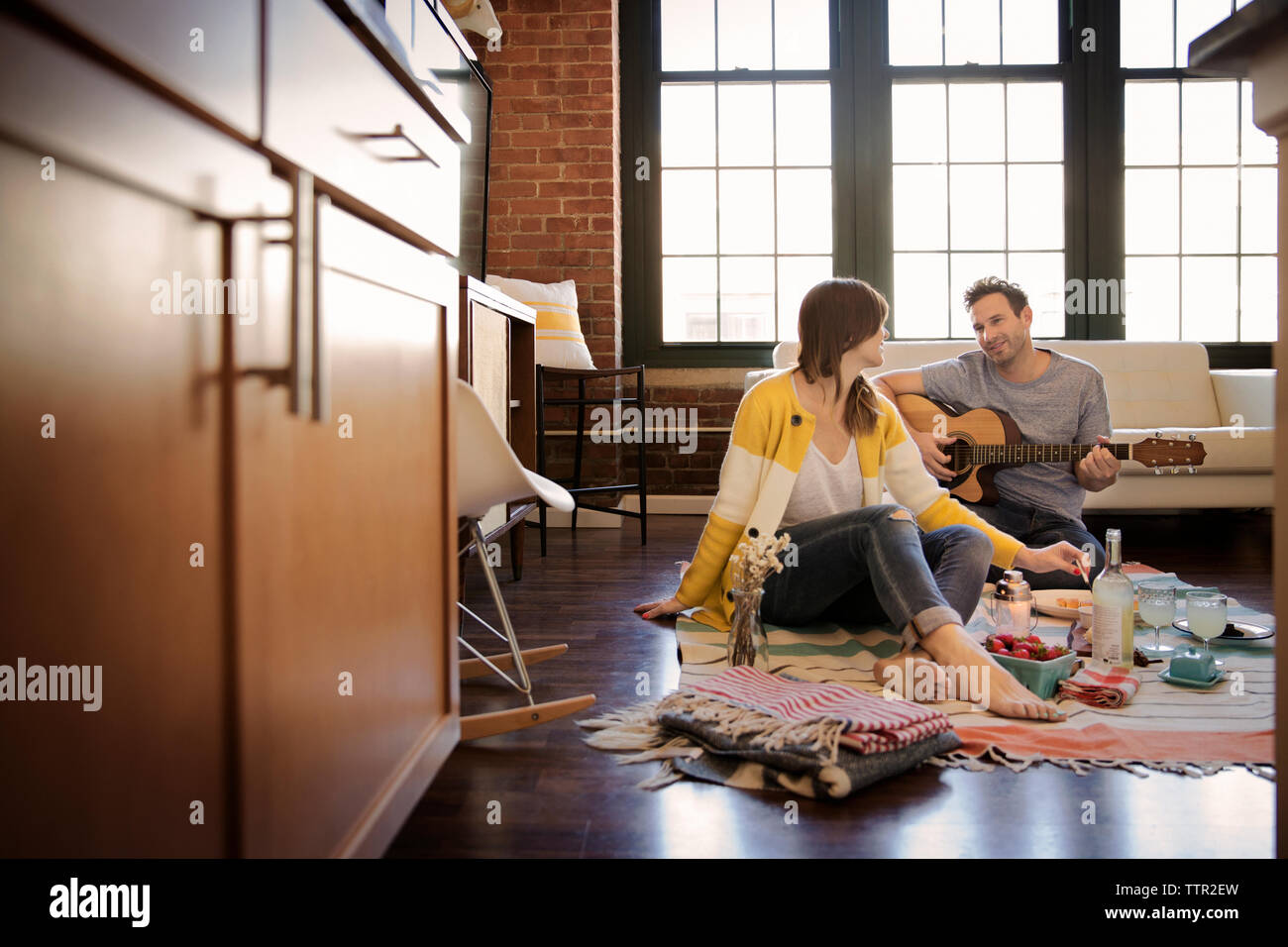 Man playing guitar for girlfriend at home Stock Photo