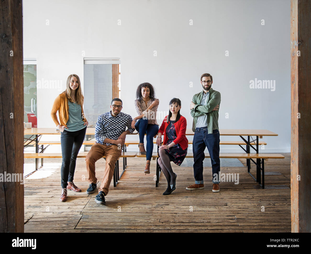 Portrait of smiling business people by bench at creative office Stock ...