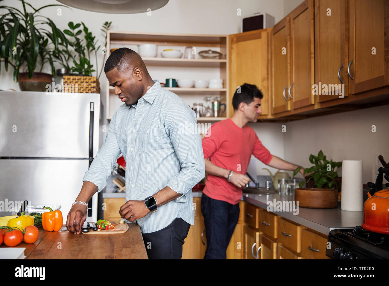Homosexual males preparing food in kitchen Stock Photo