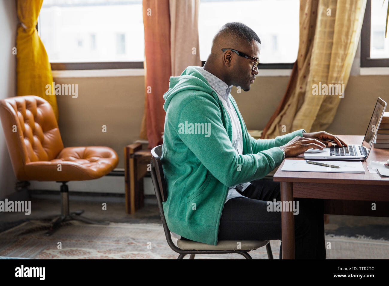 Side view of man using laptop at table Stock Photo