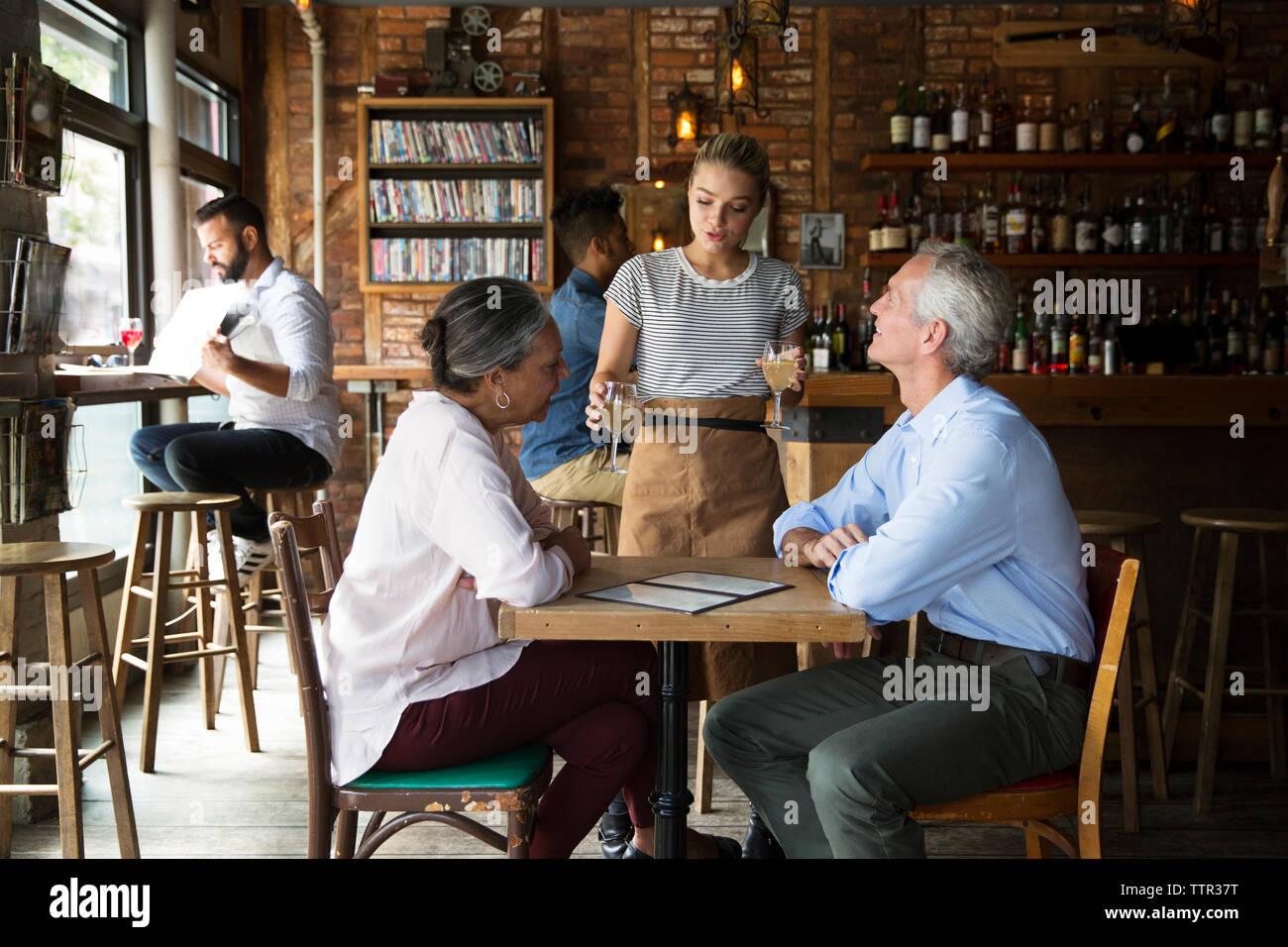 Waitress serving drinks to customers at cafe Stock Photo