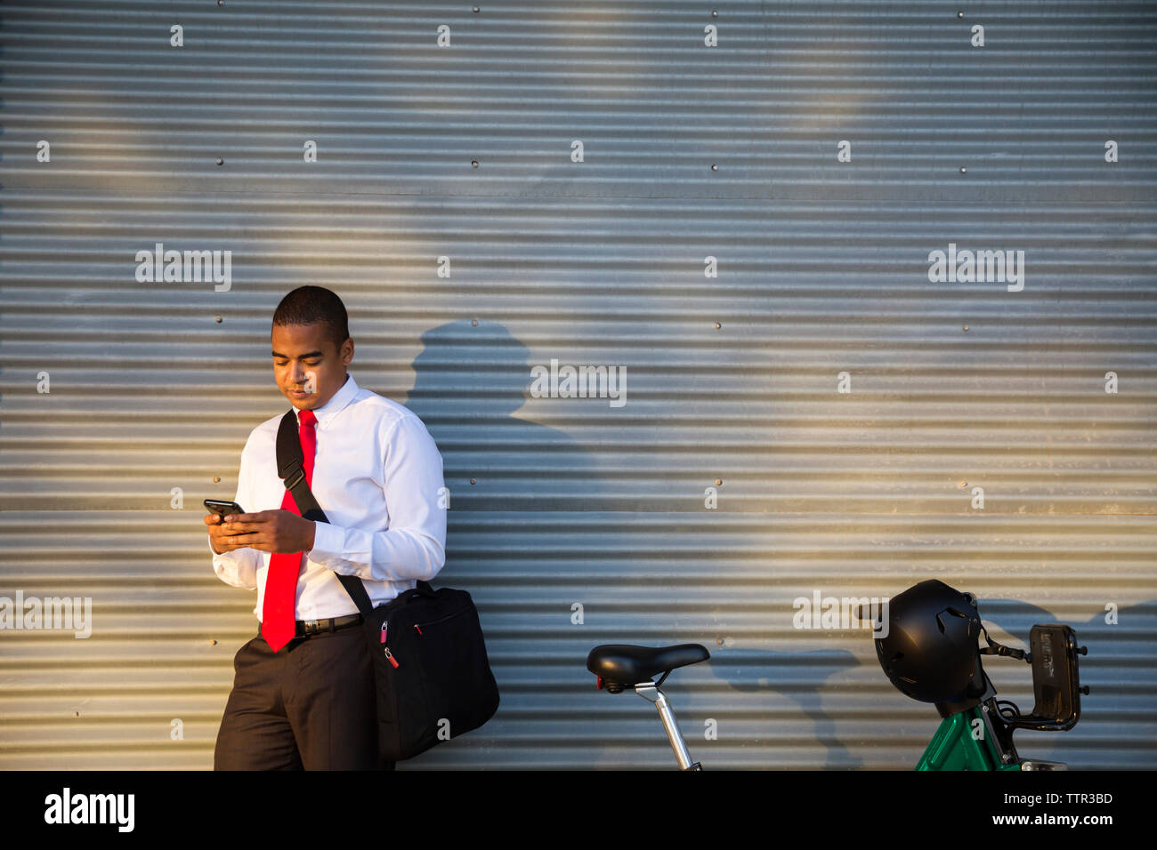 businessman using mobile phone while standing against closed shutter Stock Photo
