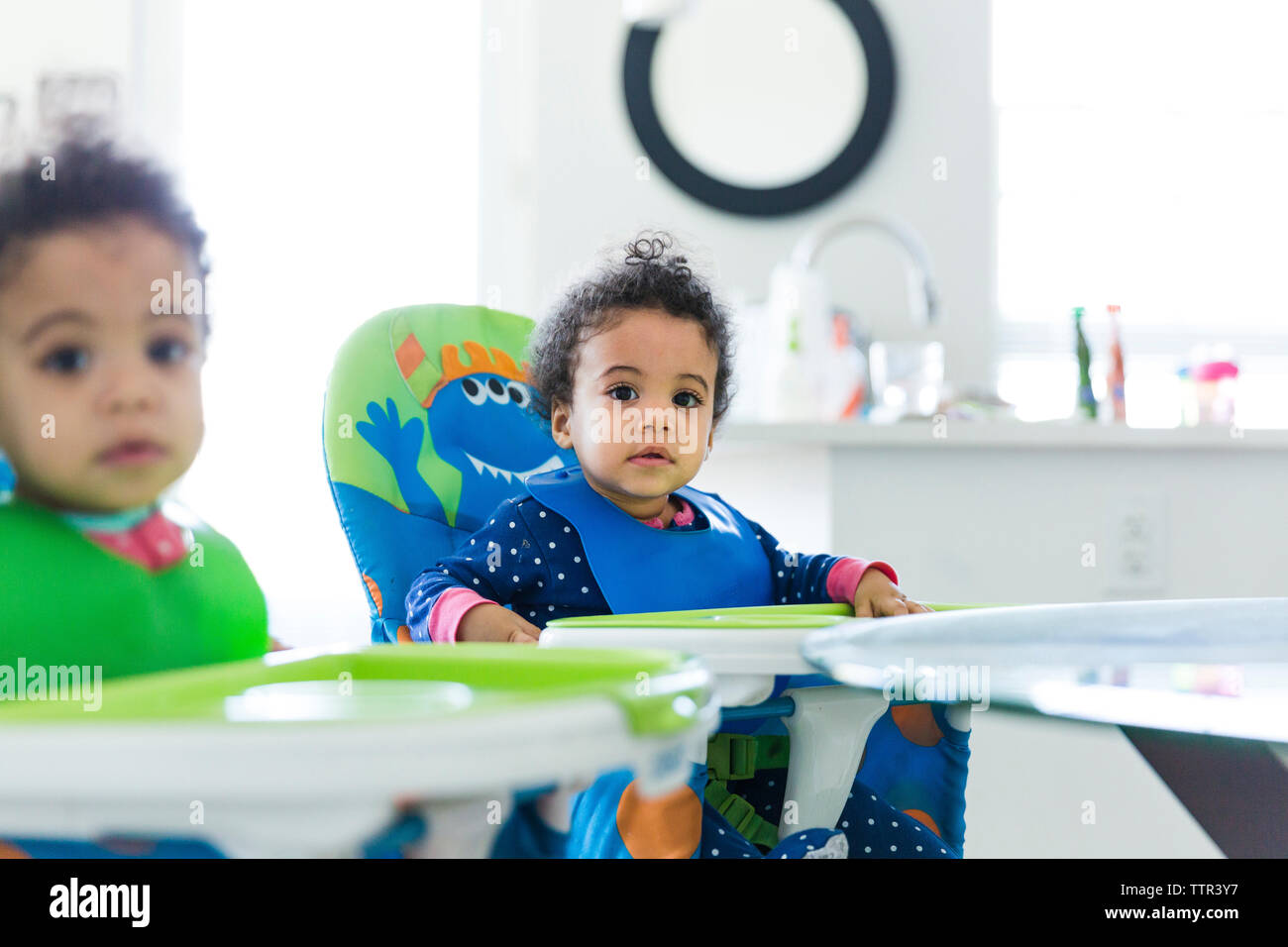 Portrait of baby girls sitting on high chairs at home Stock Photo