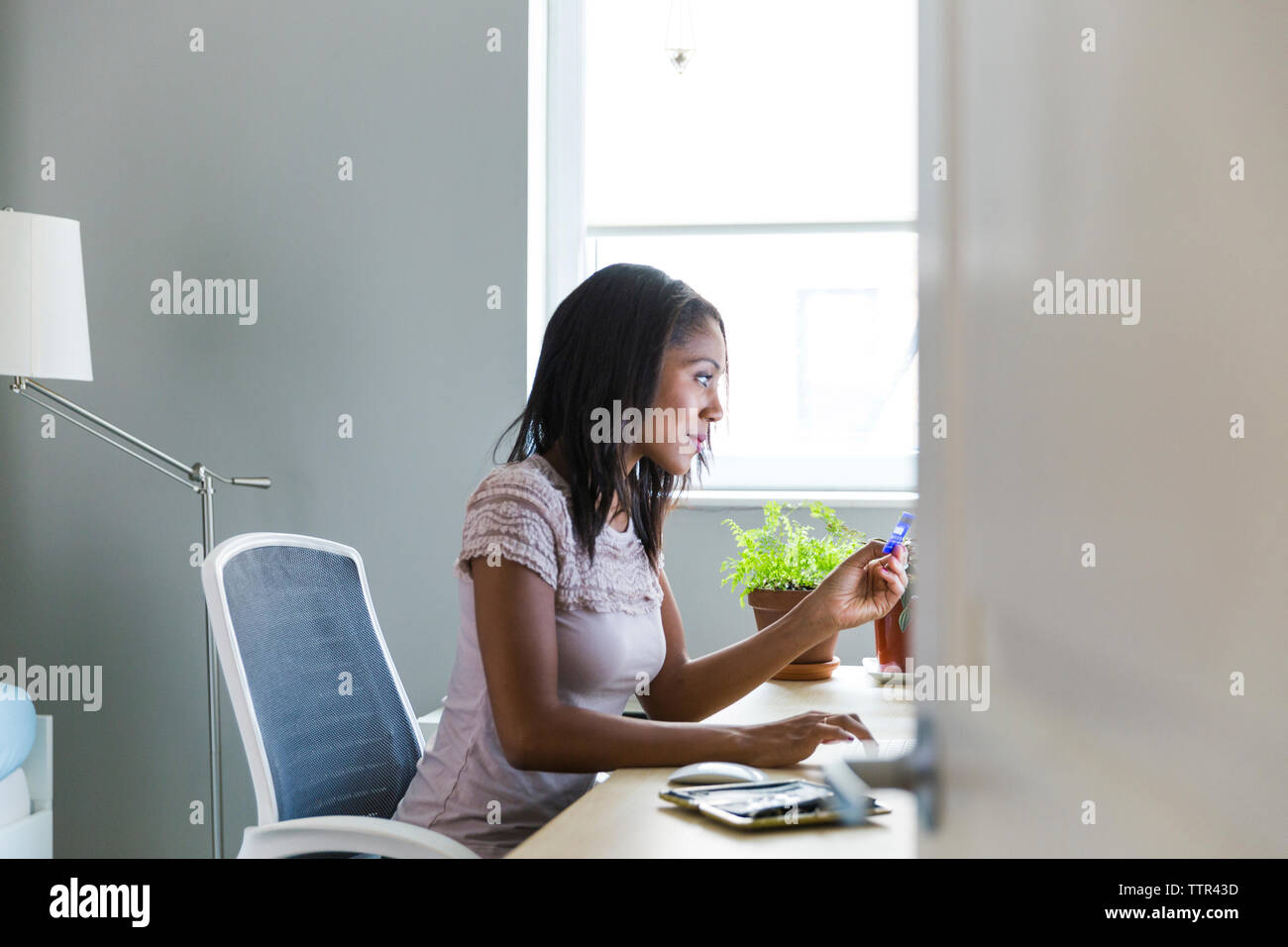 Woman working at home office seen through doorway Stock Photo