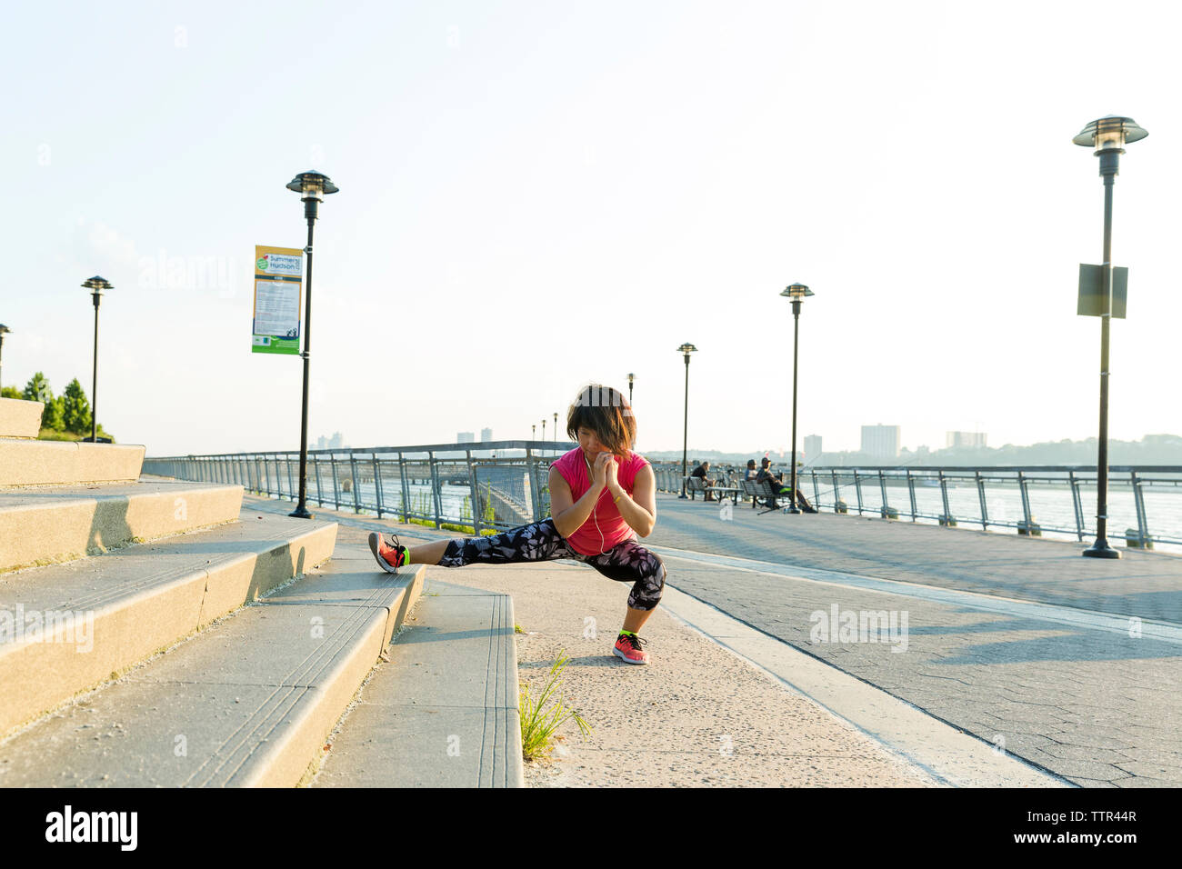 Full length of woman exercising on steps against clear sky Stock Photo