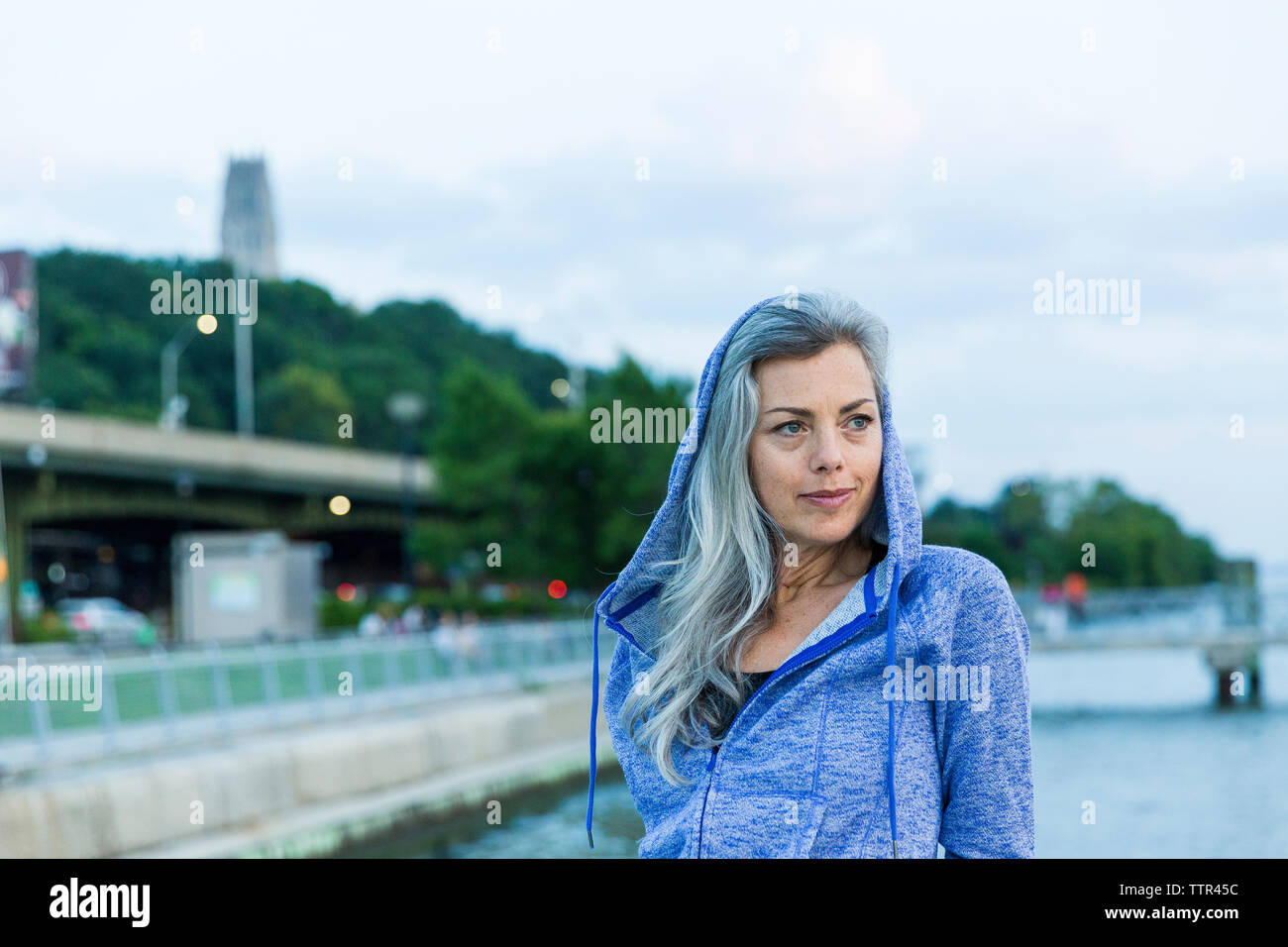 Thoughtful woman wearing hooded jacket while looking away Stock Photo