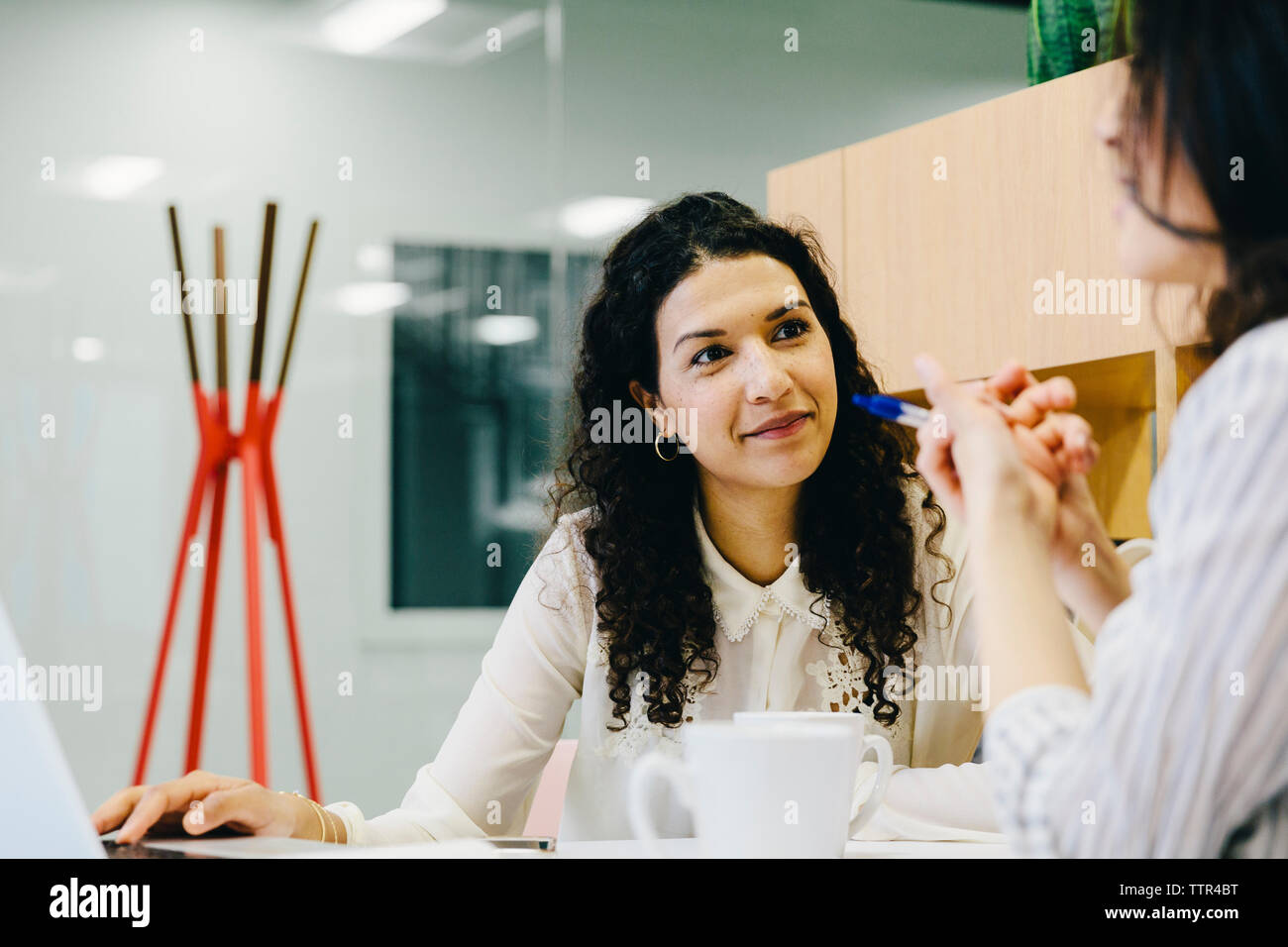 Female entrepreneurs discussing while sitting at desk in office Stock Photo