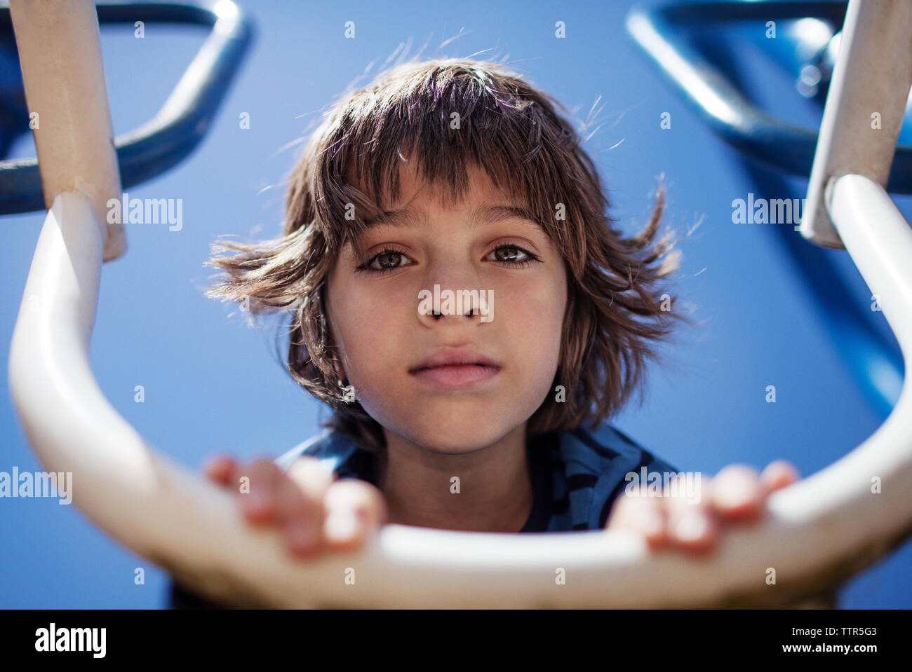 Boy leaning on outdoor play equipment at playground Stock Photo