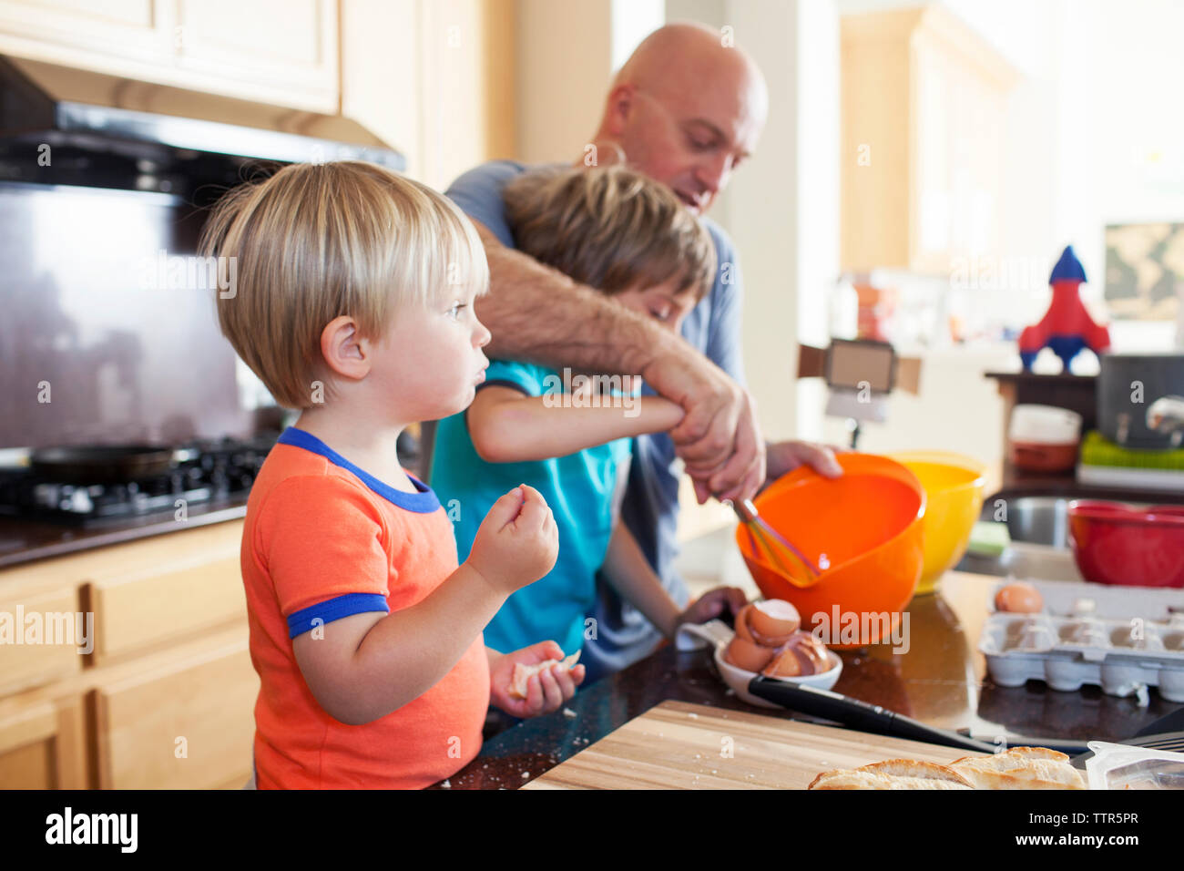 Father teaching children to prepare food in kitchen at home Stock Photo