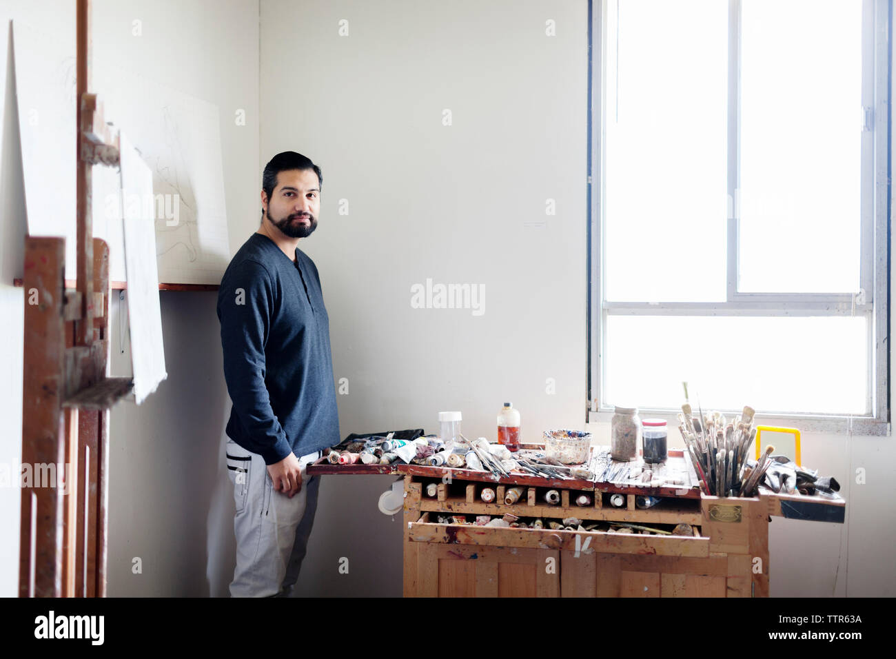 Portrait of painter standing by painting tools in art studio Stock Photo