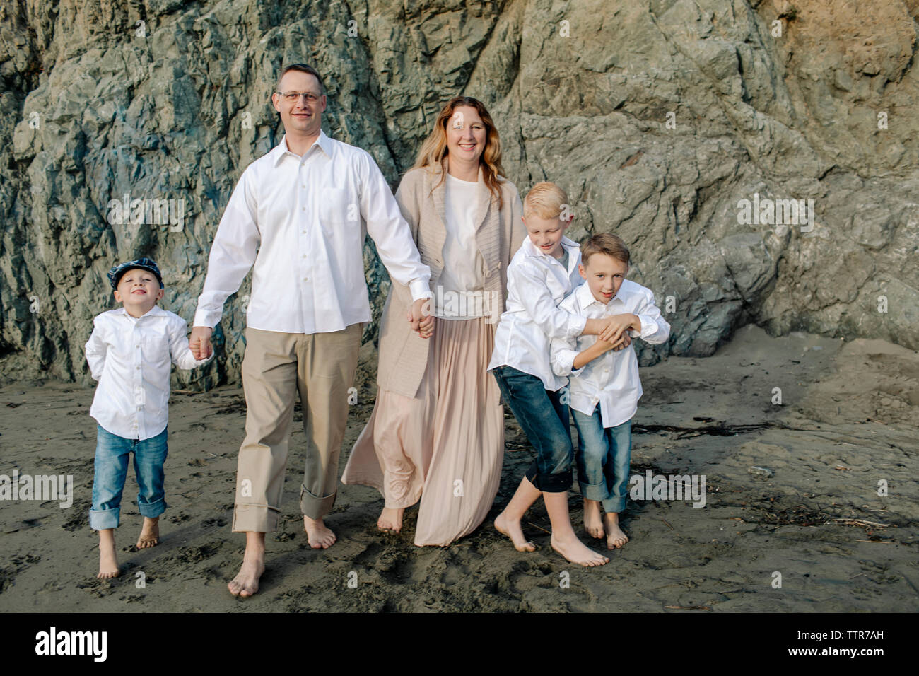 Family holding hands on rock by the sea Stock Photo