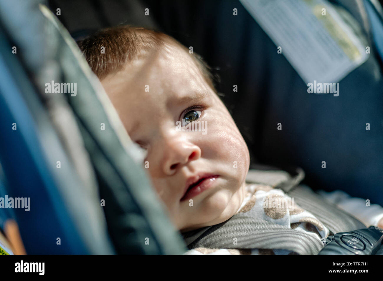 Cute baby looking away while in car-seat Stock Photo