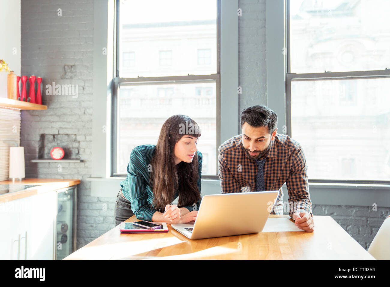 Man and woman using laptop computer while standing at table in office Stock Photo