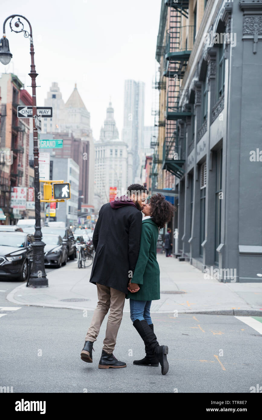 Full length of business couple kissing while standing on city street Stock Photo