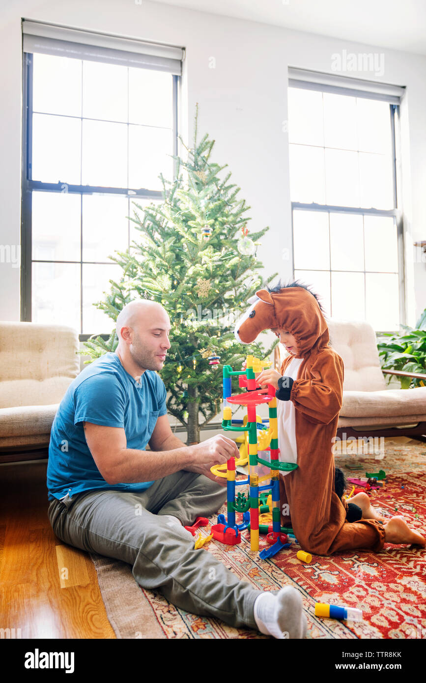 Father playing toy blocks with son dressed in costume at home Stock Photo
