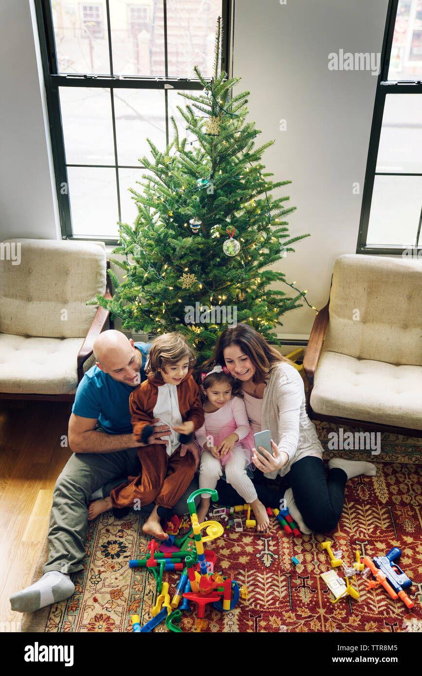 Family video conferencing while sitting against Christmas tree at home Stock Photo