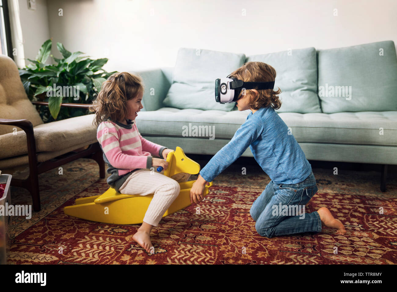 Boy Wearing Virtual Reality Simulator Playing With Sister Sitting