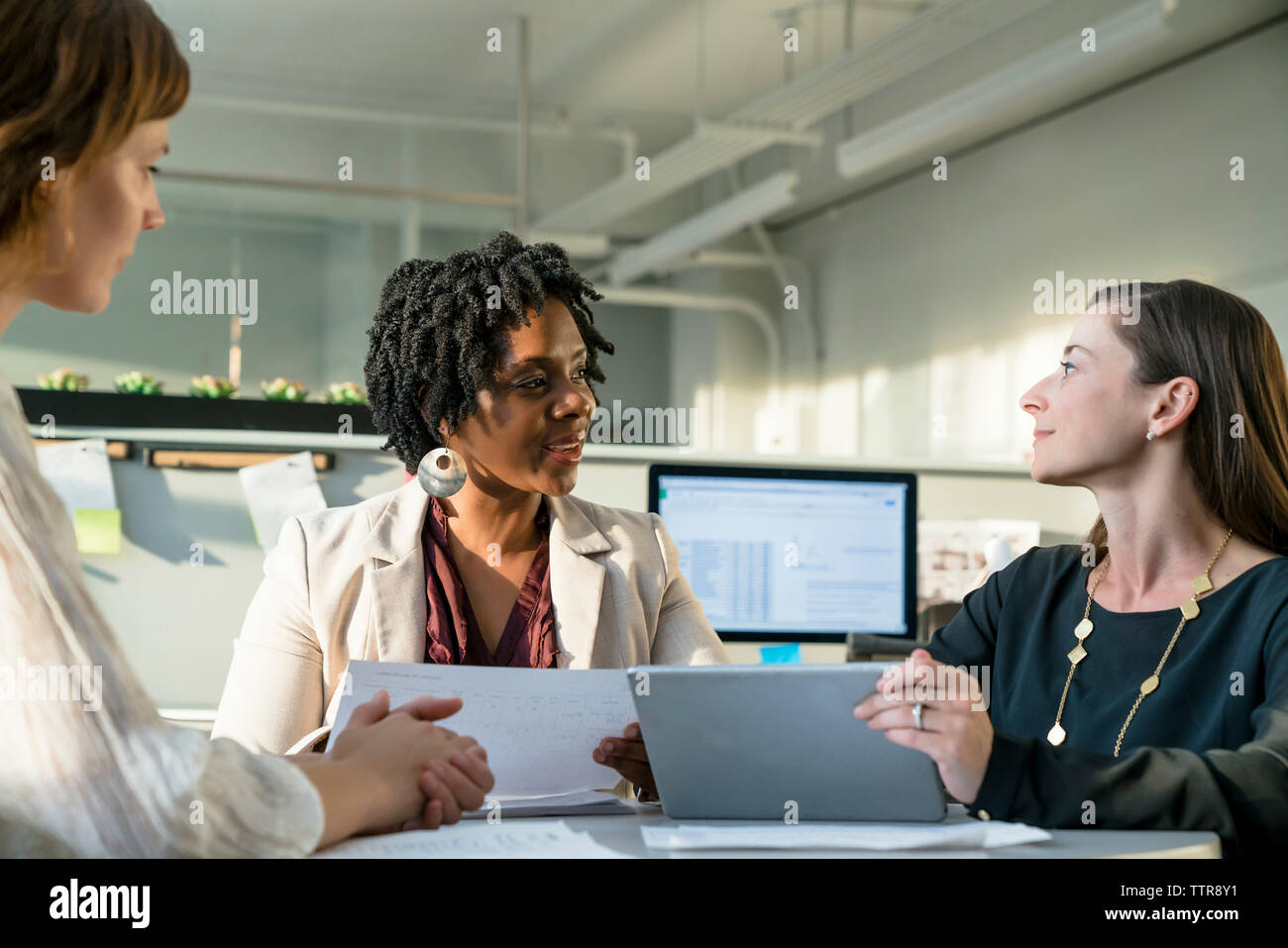 businesswomen discussing over tablet computer while sitting in office Stock Photo