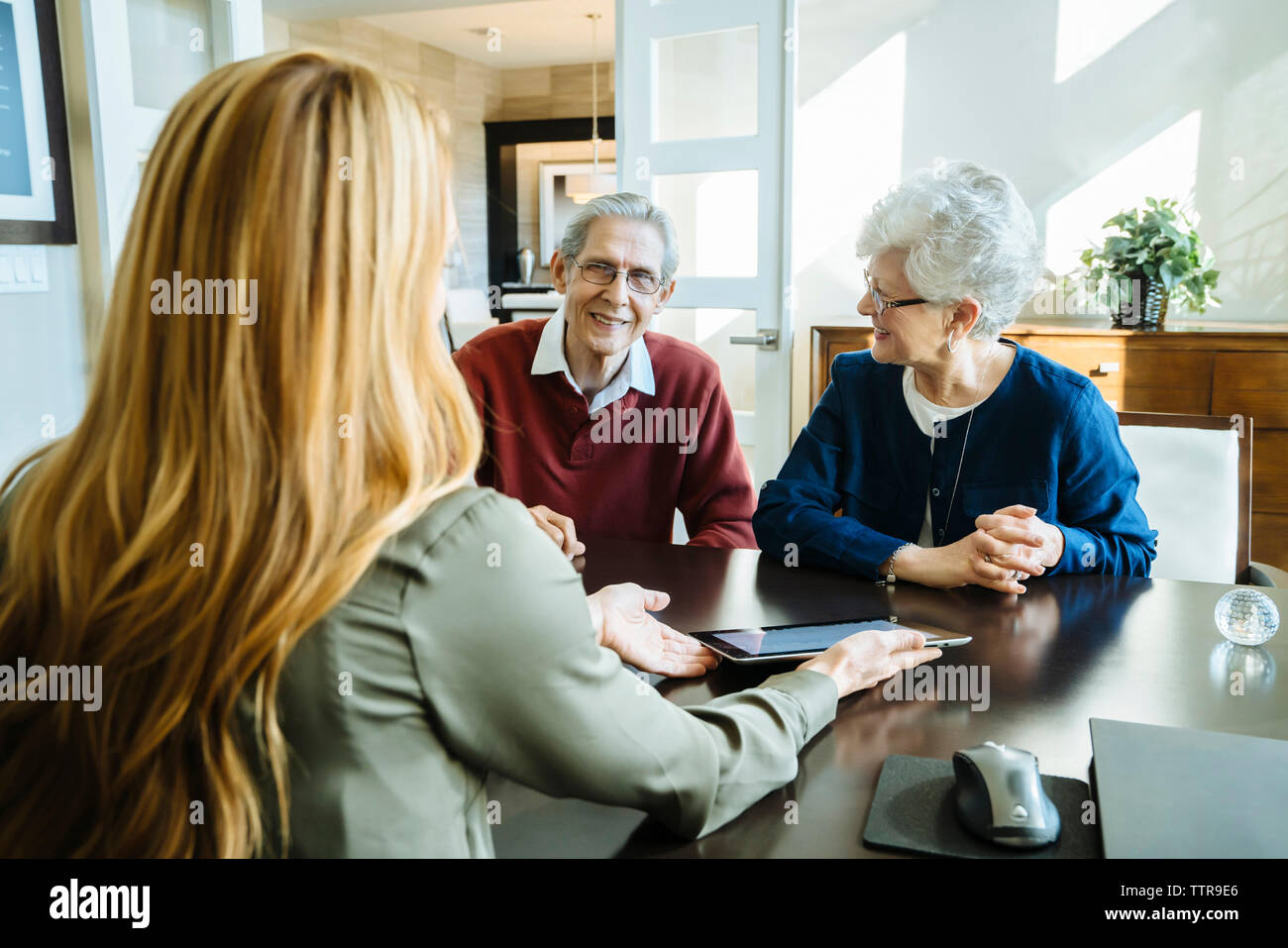 Financial advisor explaining plan to senior couple on tablet computer in office Stock Photo