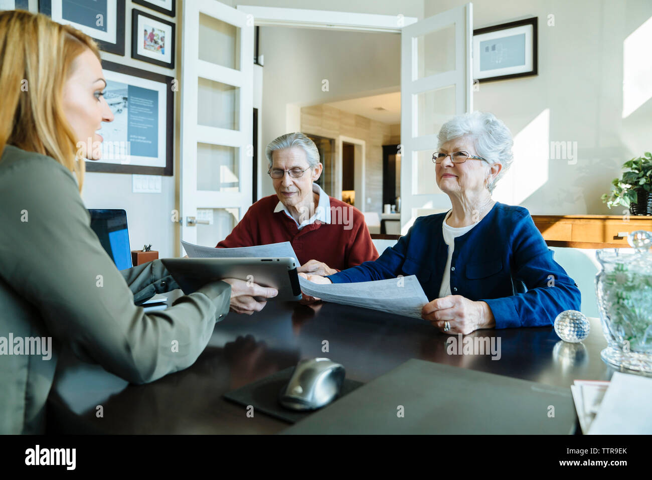 Senior couple holding documents while discussing with financial advisor in office Stock Photo