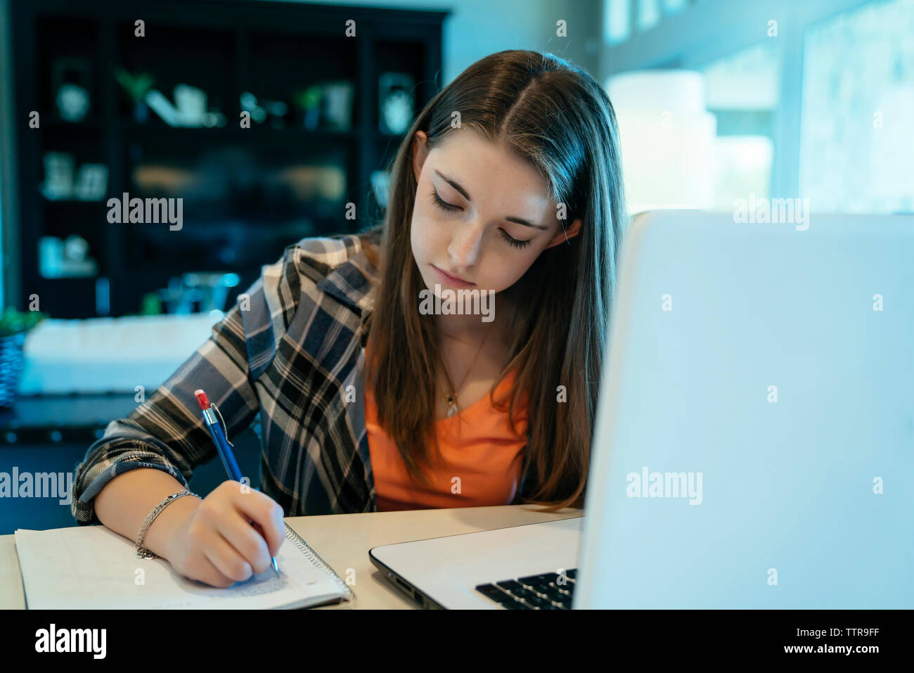 Teenage girl doing homework using laptop computer at home Stock Photo