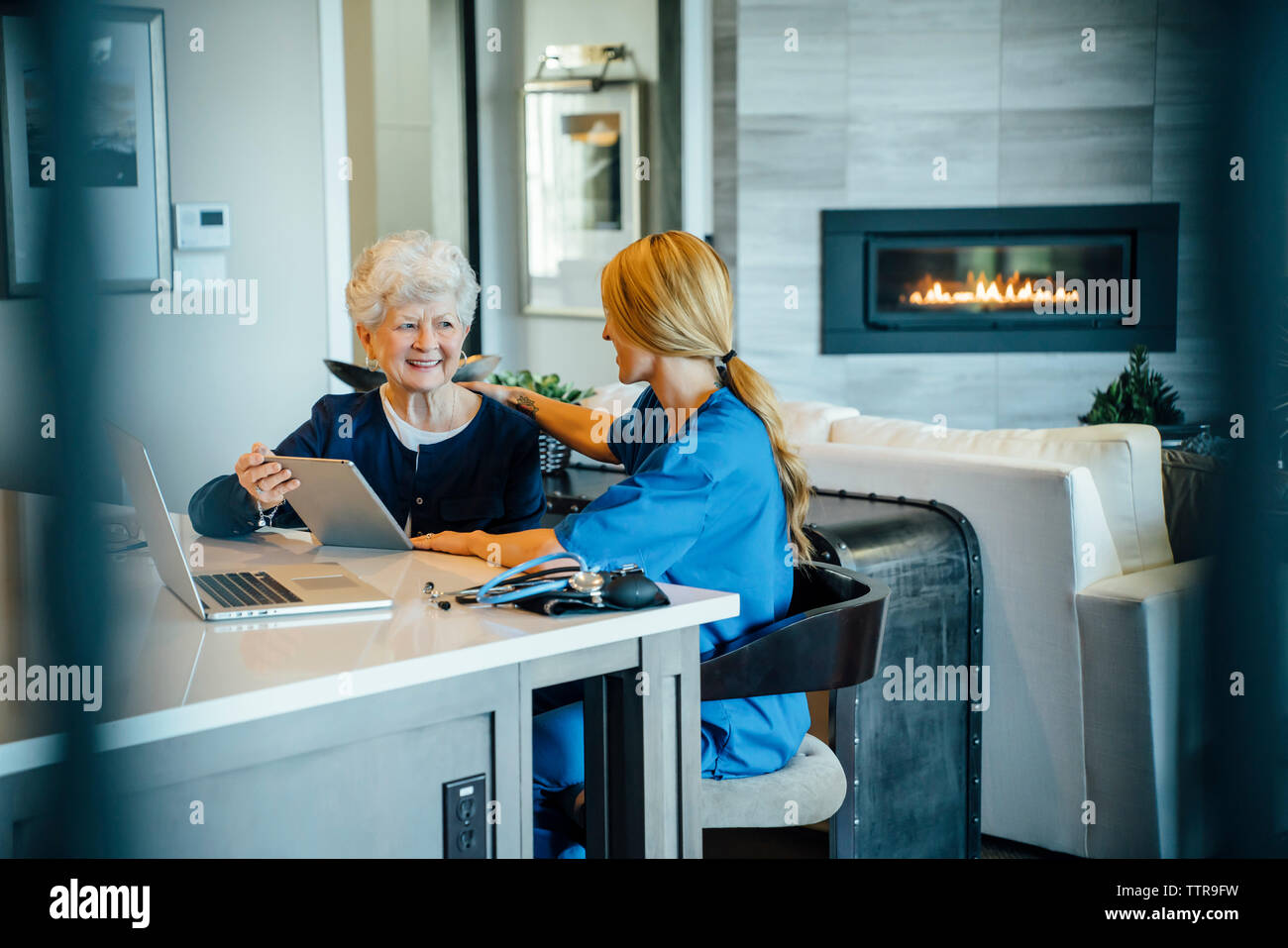 Senior woman using tablet computer with home caregiver Stock Photo