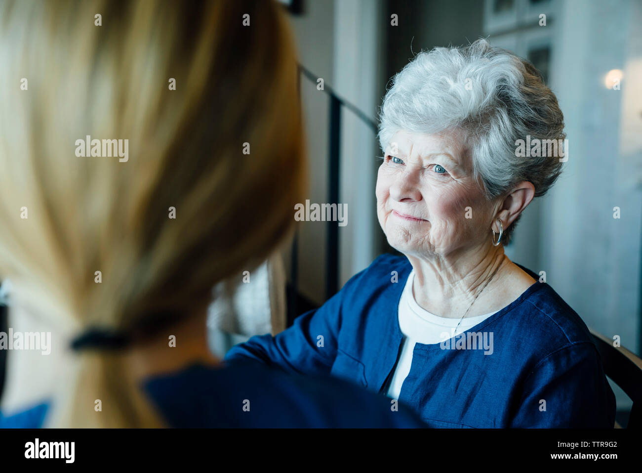 Happy senior woman looking at home caregiver Stock Photo